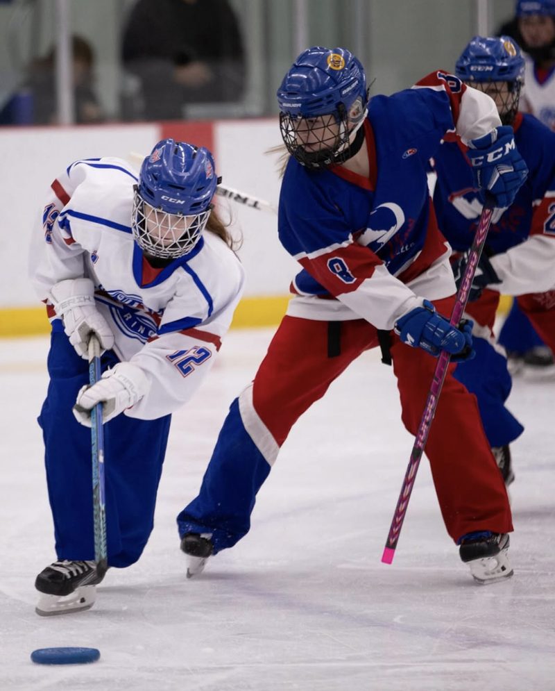 Two ringette players contesting the ring at speed